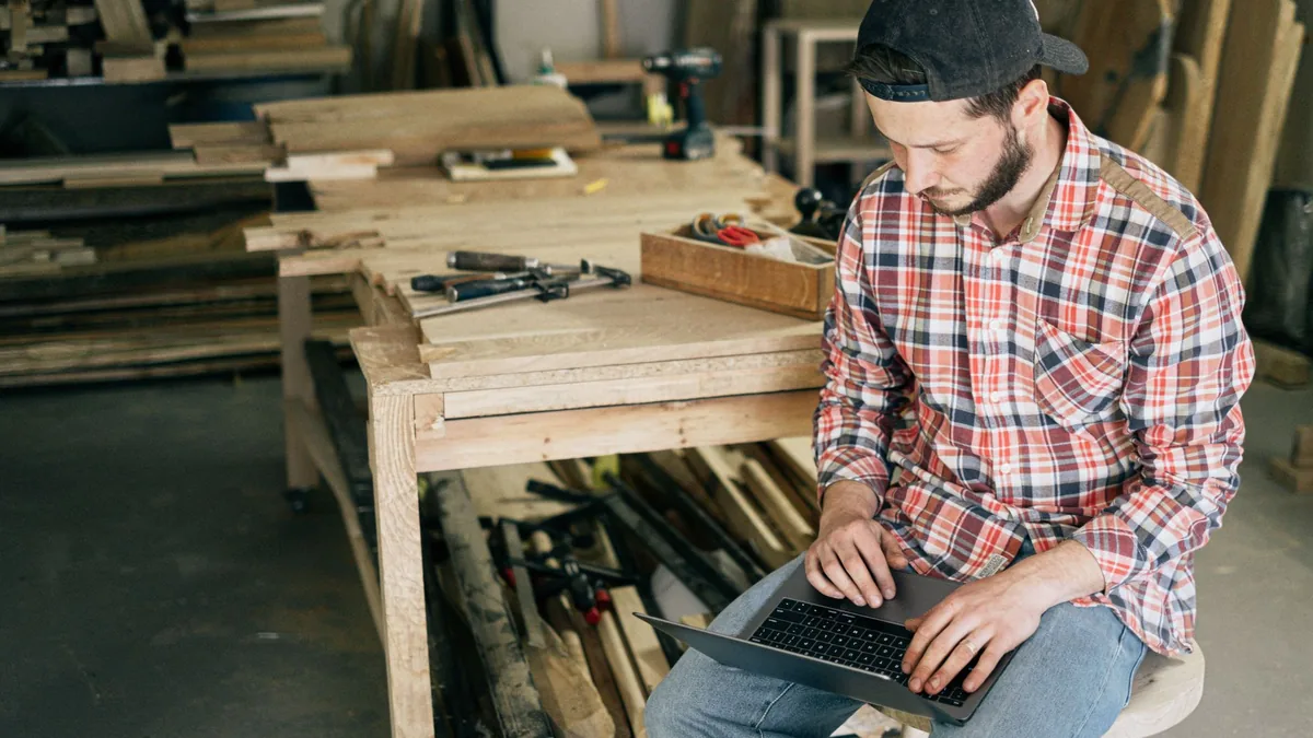 Carpenter checking his laptop in a woodworking workshop