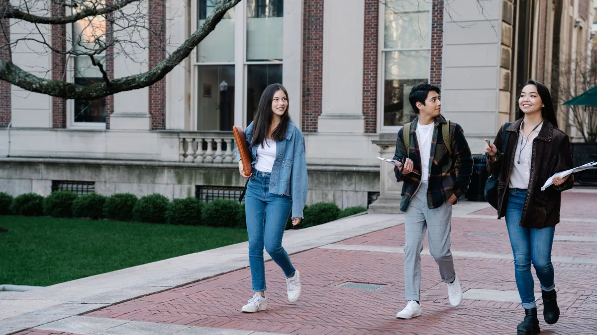 Group of university students walking across a sunny campus