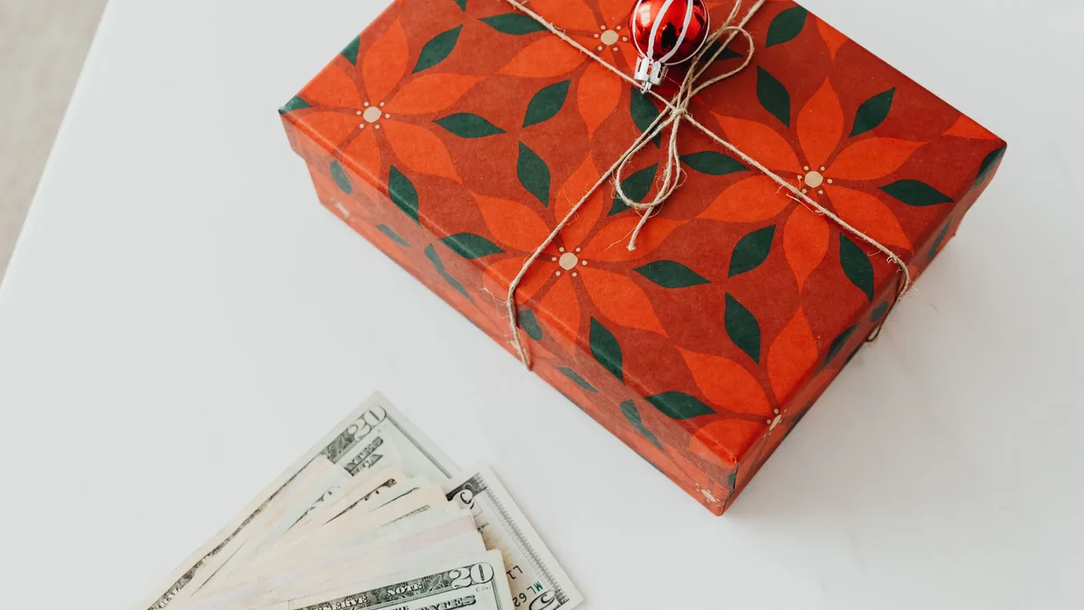 Christmas gift box tied with string next to banknotes on a white table