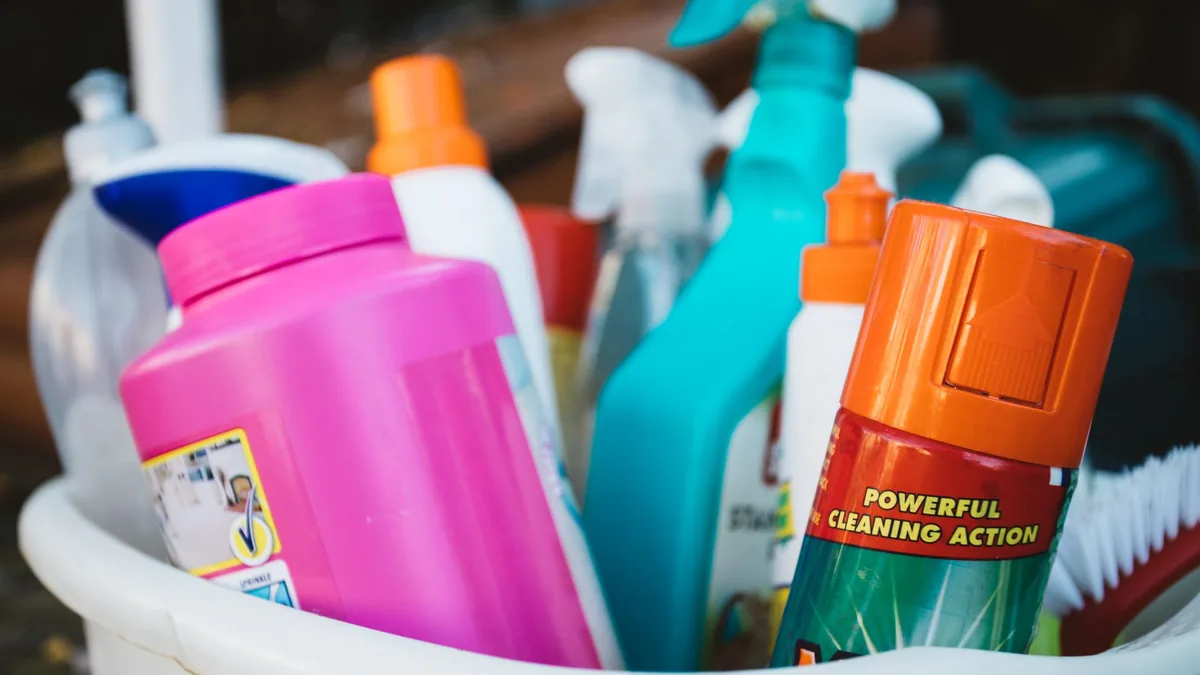 Bucket of colourful cleaning sprays and detergents