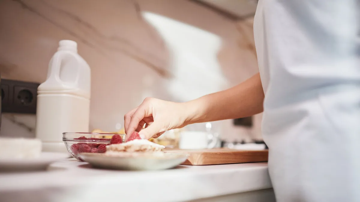 Person preparing a fresh raspberry dish on a bright kitchen counter