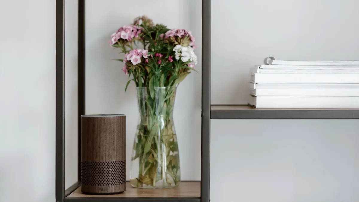 Tidy shelf with a vase of flowers, a smart speaker and stacked books