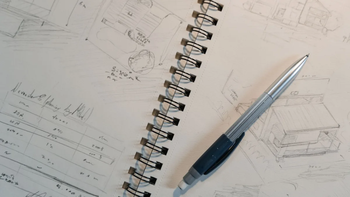 Pencil sketches and design notes on a spiral notepad with a mechanical pencil