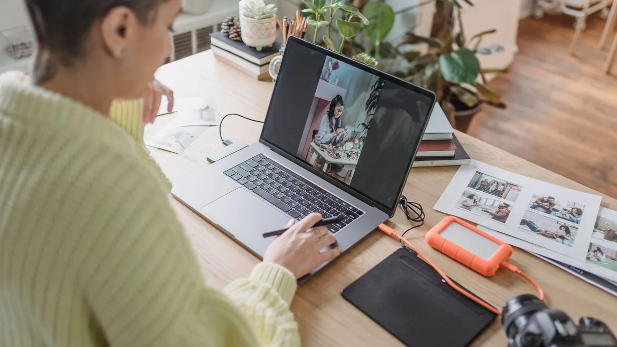 Woman editing photos on her laptop at a desk with photography kit