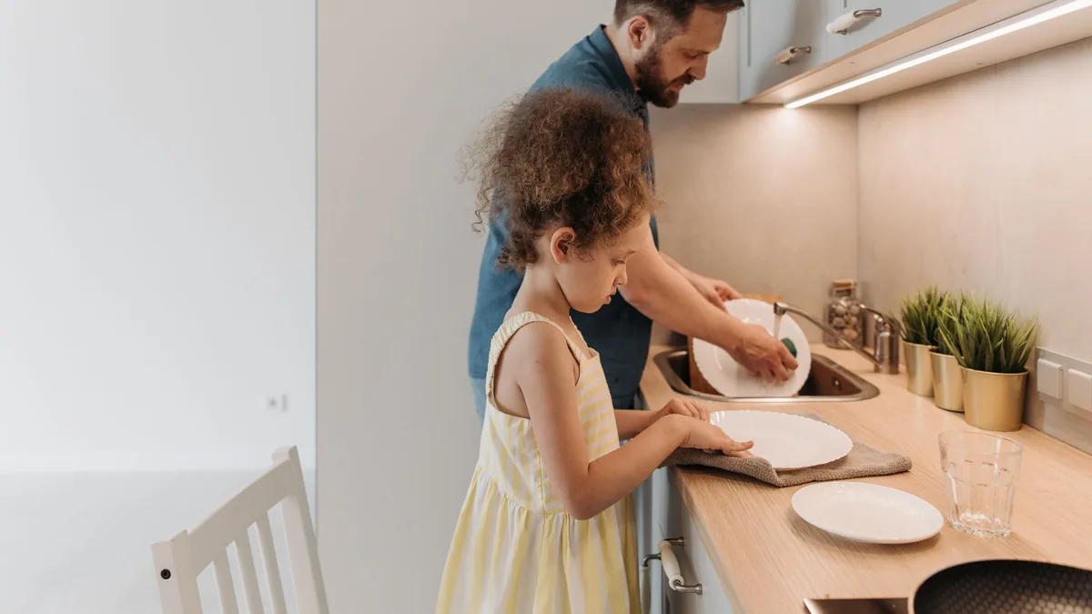 Father and daughter washing up together in the kitchen