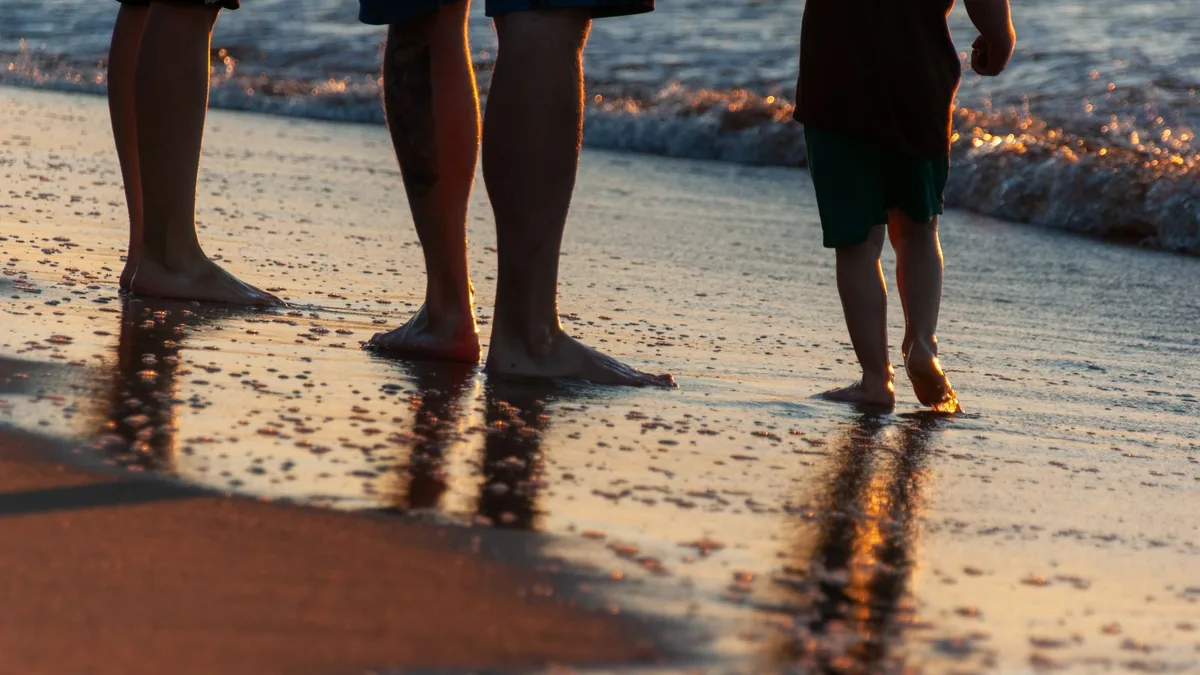 Family silhouetted walking along the beach at sunset