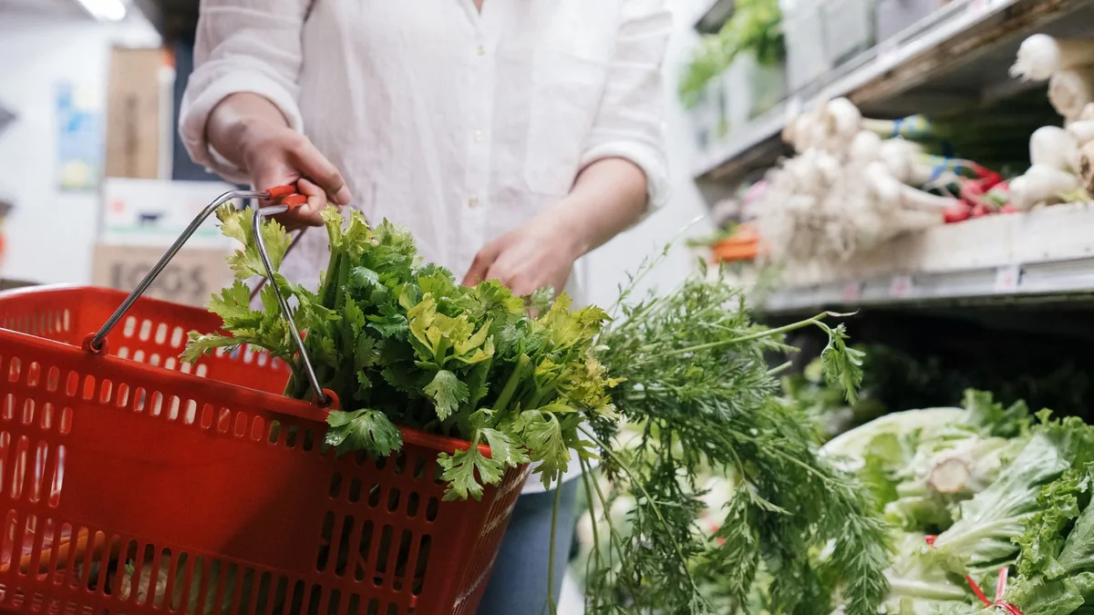 Shopping basket filled with fresh celery and greens in a shop