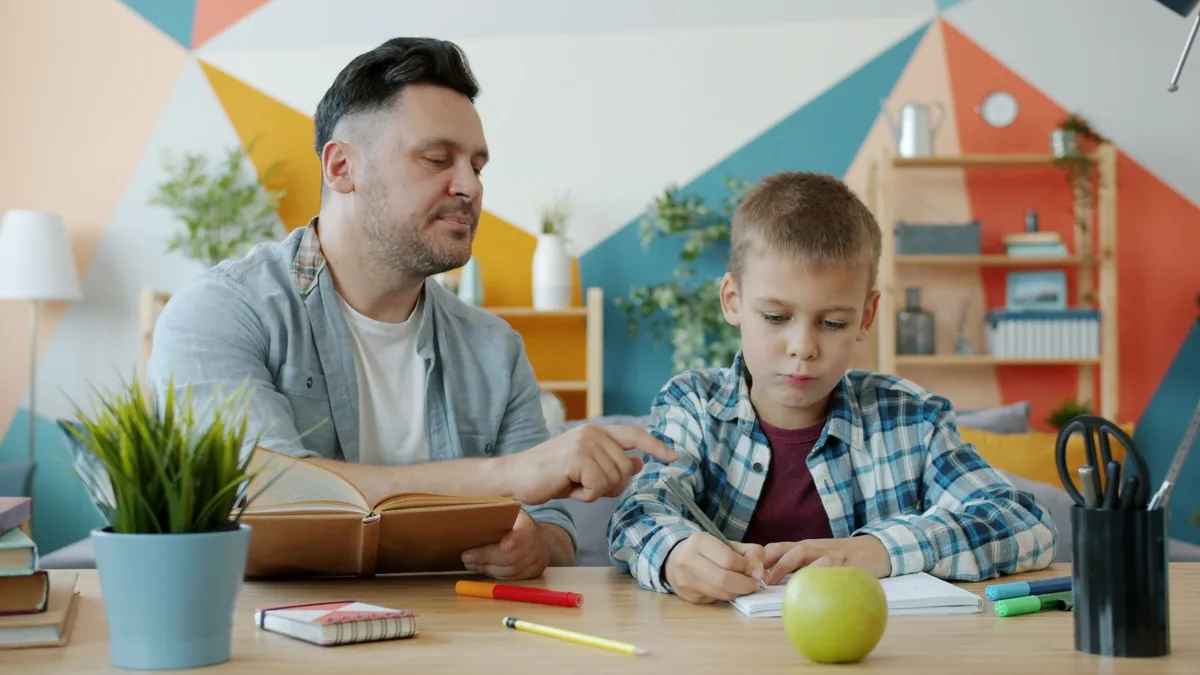 Father helping his son with homework at a desk