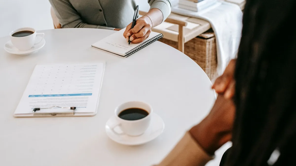 Two people talking over coffee with notes and papers on the table