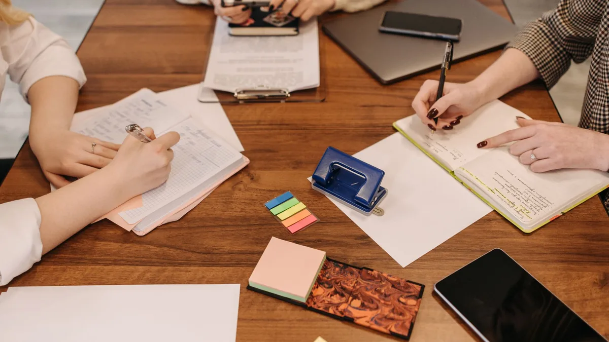 Three colleagues taking notes and reviewing documents around a table