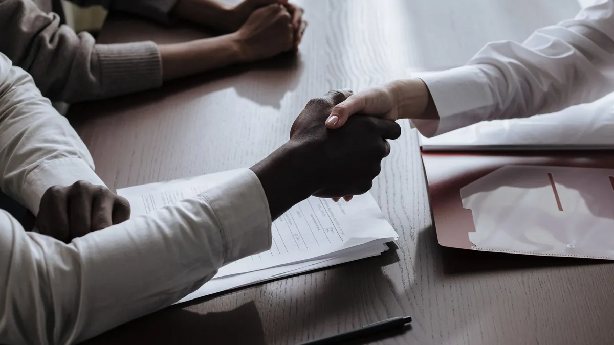Handshake over contract papers at a meeting table