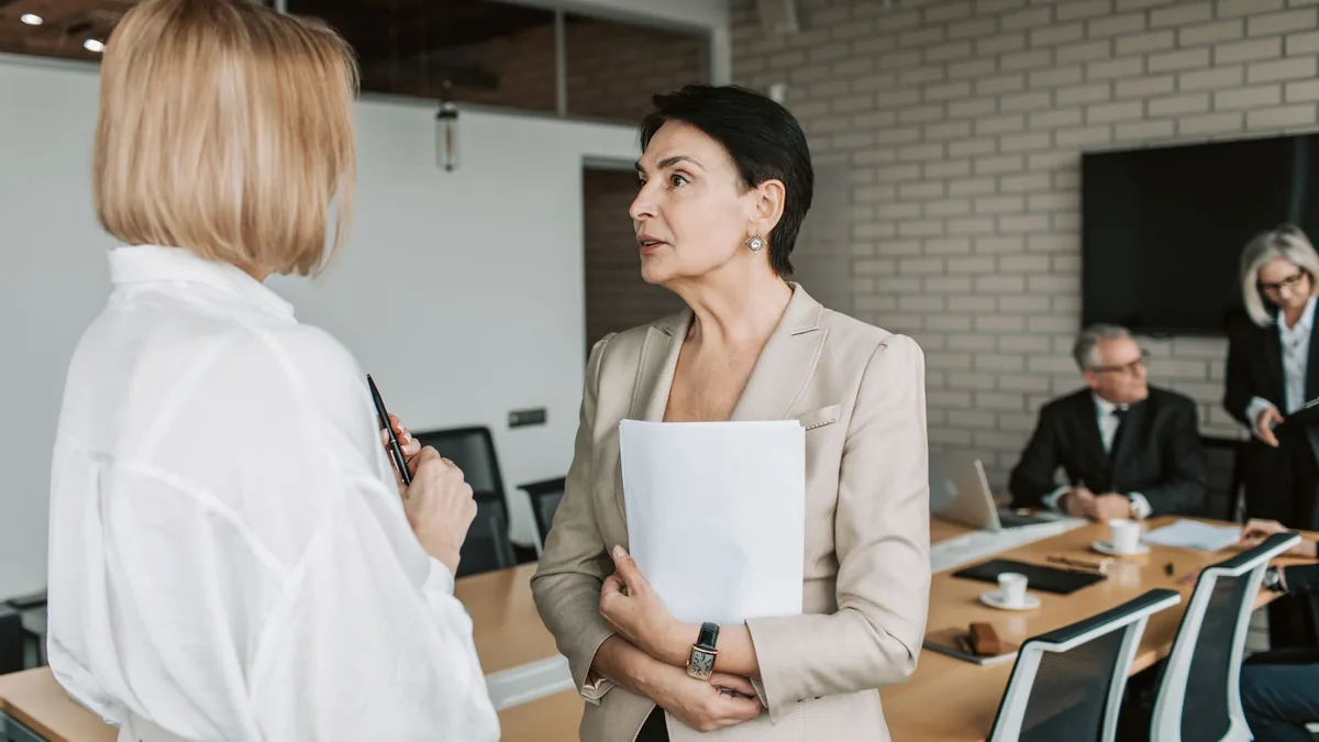 Two colleagues talking during a meeting in a modern office