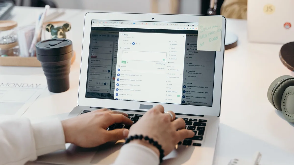 Person typing an email on a laptop next to a coffee cup
