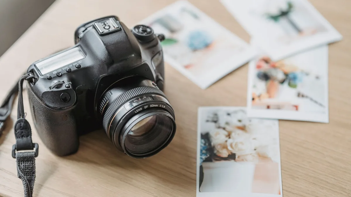 DSLR camera on a desk surrounded by printed photographs
