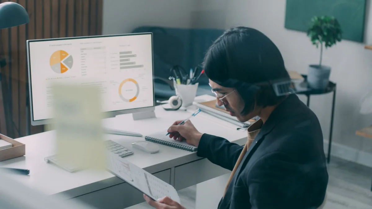 Woman at a modern office desk reviewing charts on her computer