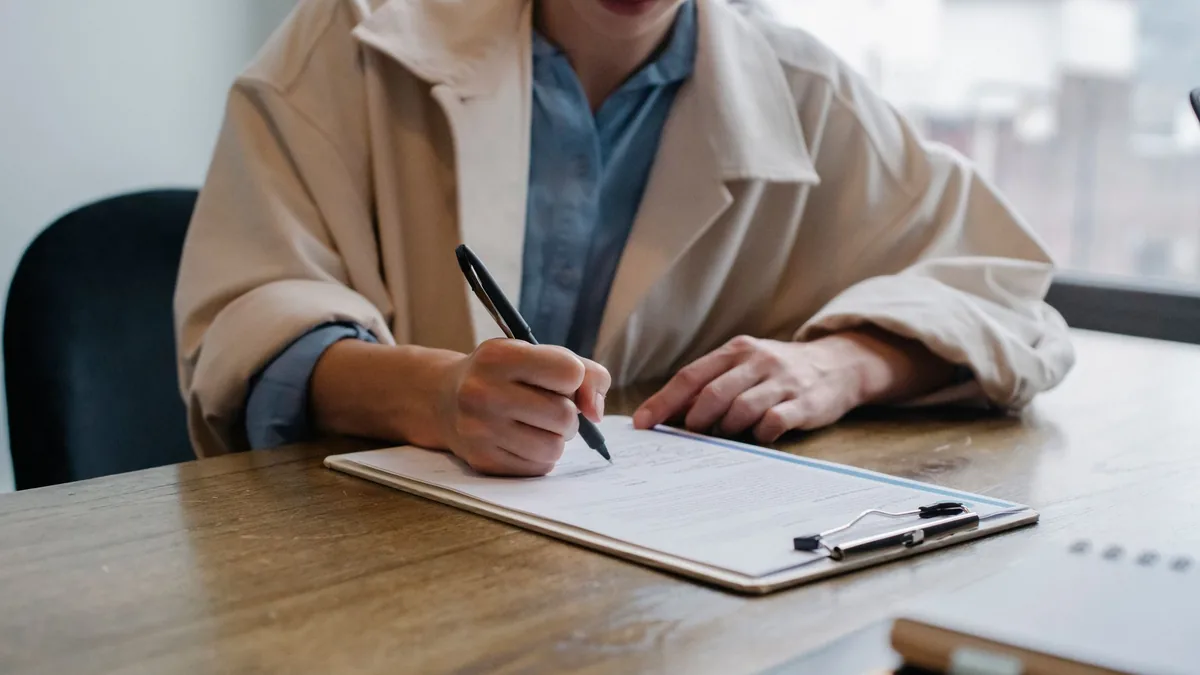 Woman filling in an application form on a clipboard at a desk