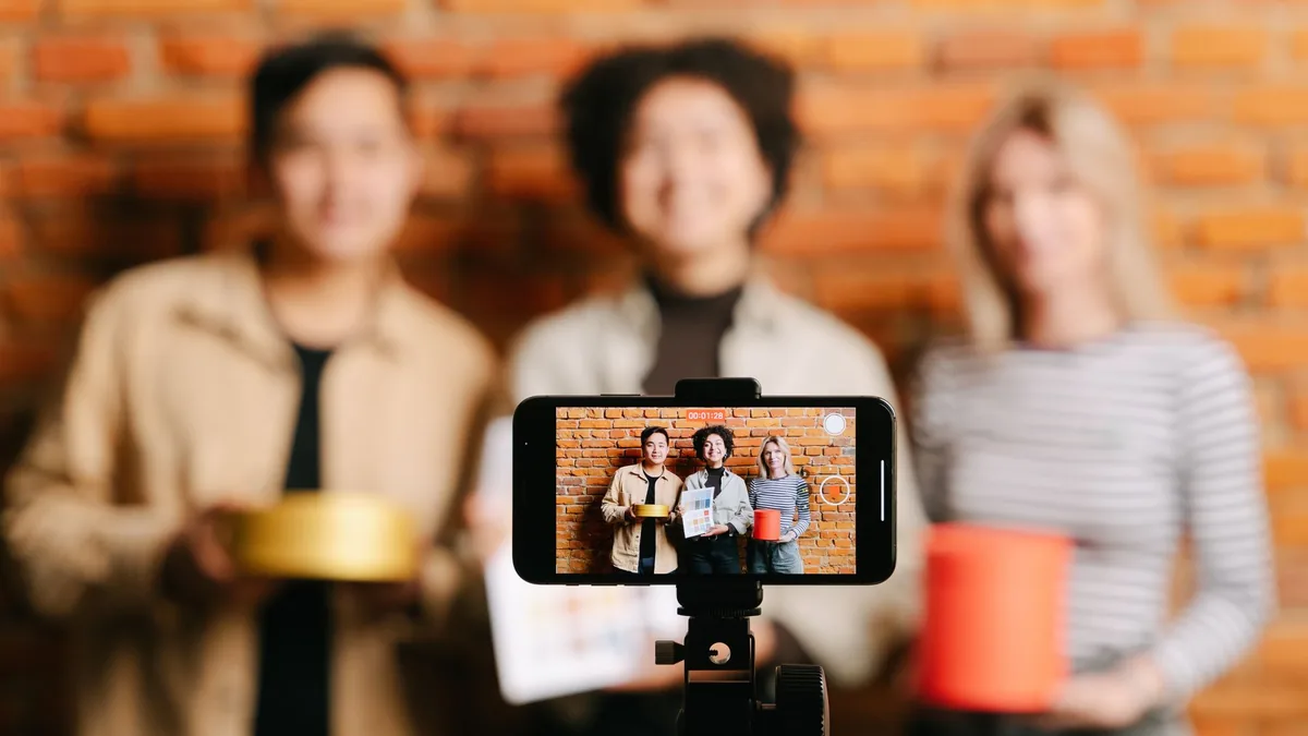 Three creators filming product content on a smartphone against a brick wall