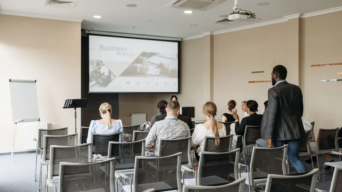 Audience in an office meeting room watching a presentation on a projector screen