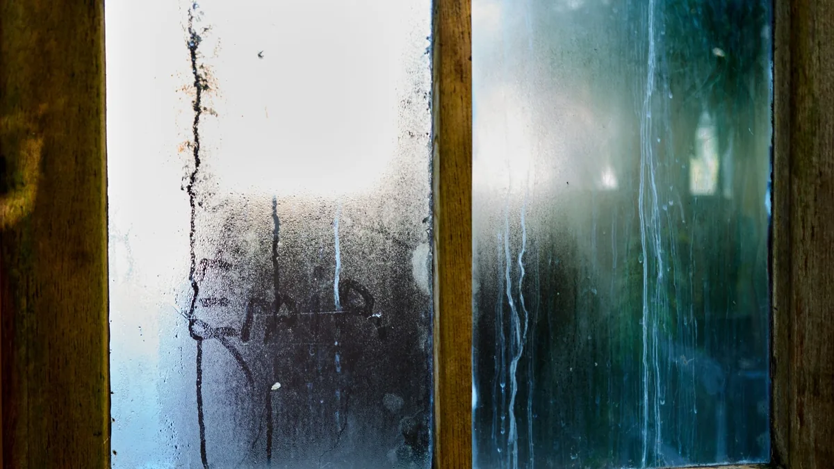 Condensation streaks on the inside of a wooden-framed window