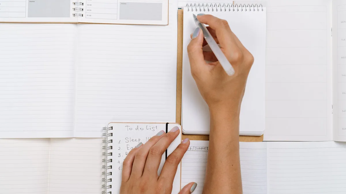 Hands writing a to-do list on notepads