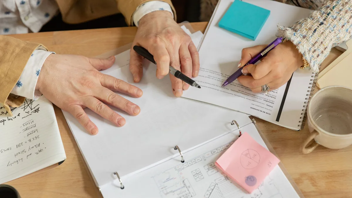 Two colleagues planning a project over documents and notes