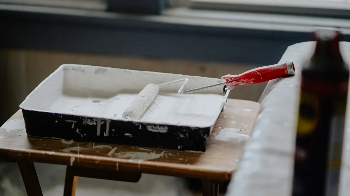Paint roller and tray of white paint on a table, ready for decorating