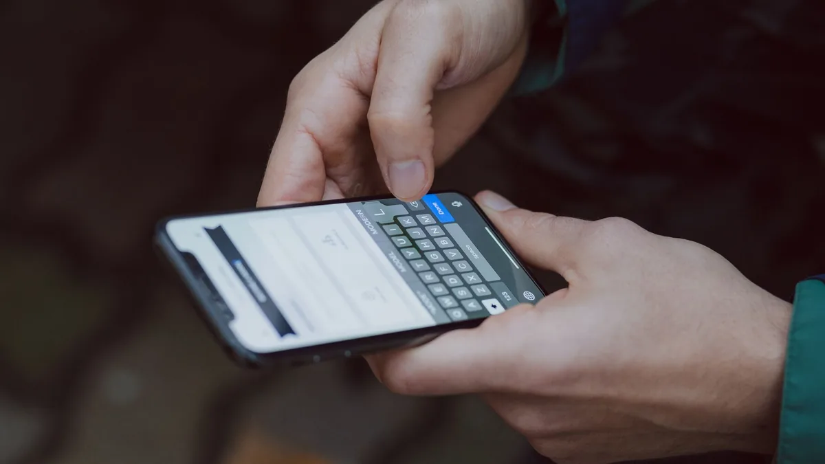 Close-up of hands typing a message on a smartphone