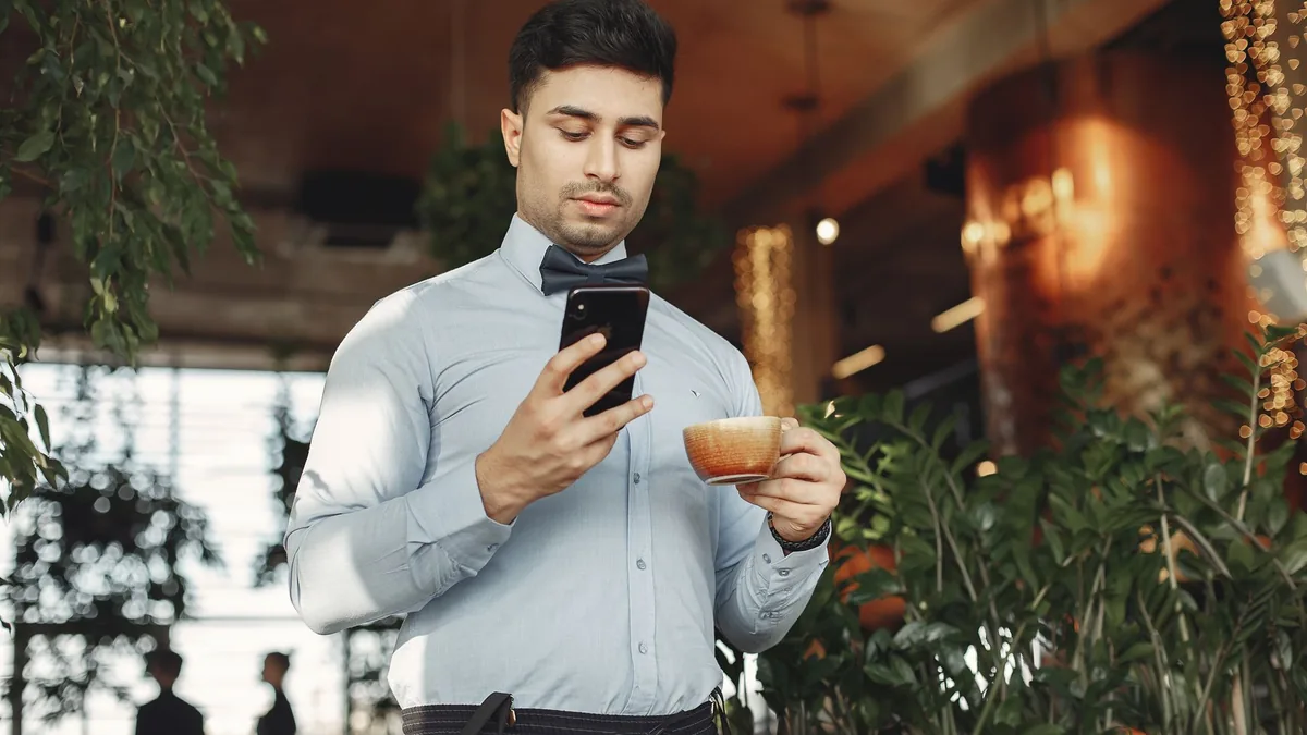 Young man in a café checking his phone over a coffee