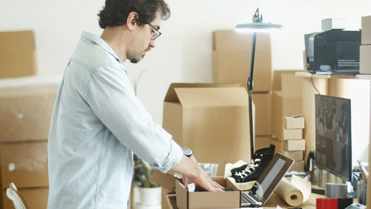 Man packing boxes at his desk surrounded by cardboard boxes