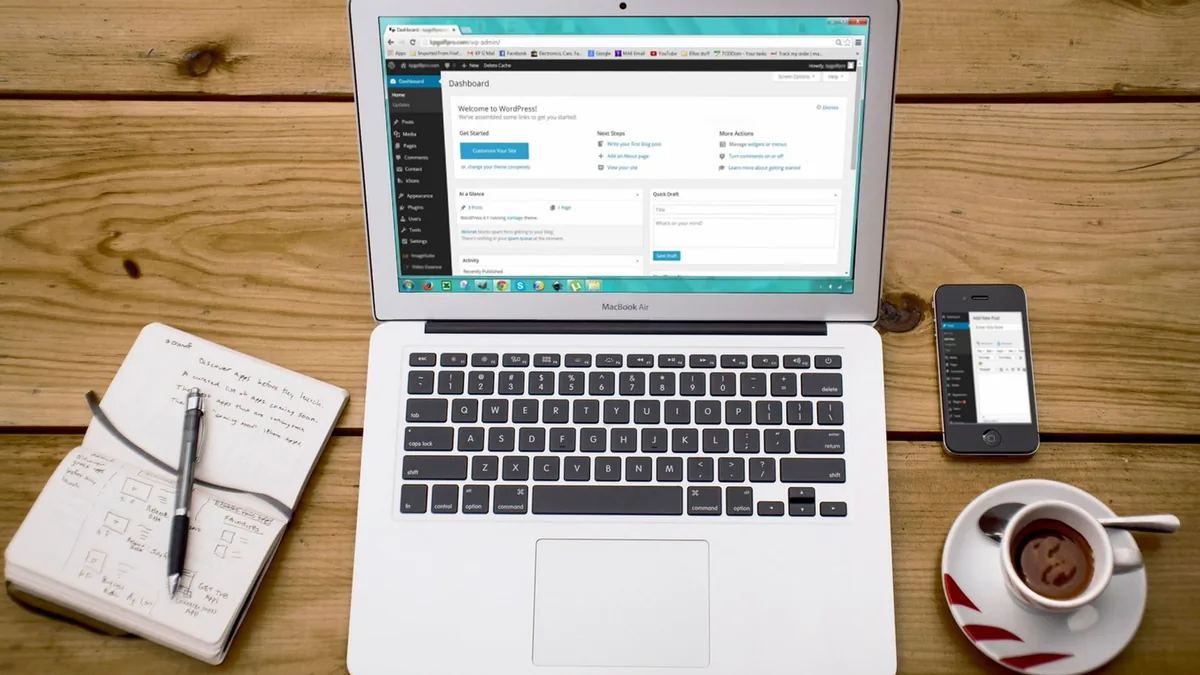 Laptop, notebook, smartphone and coffee on a wooden desk
