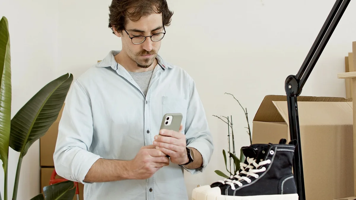 Small business owner photographing trainers with his phone for an online shop
