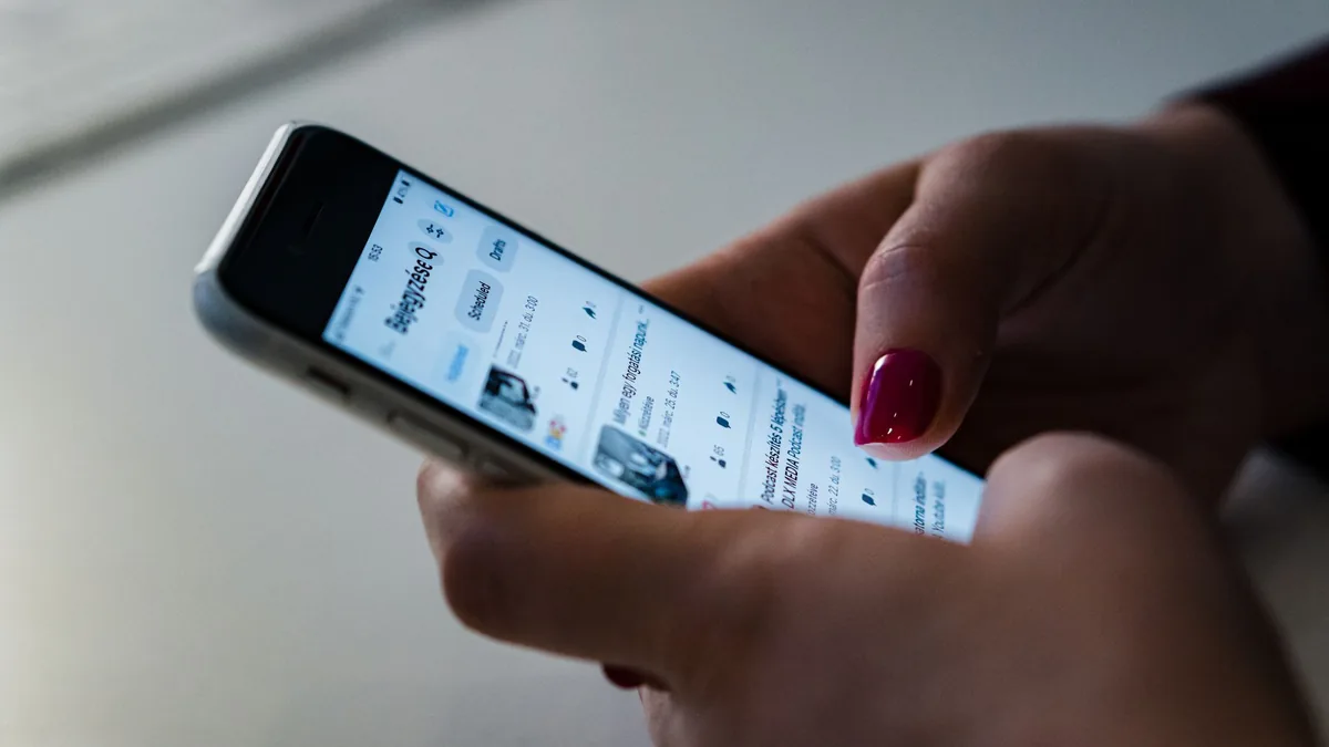 Close-up of hands holding a smartphone and scrolling through a social media feed