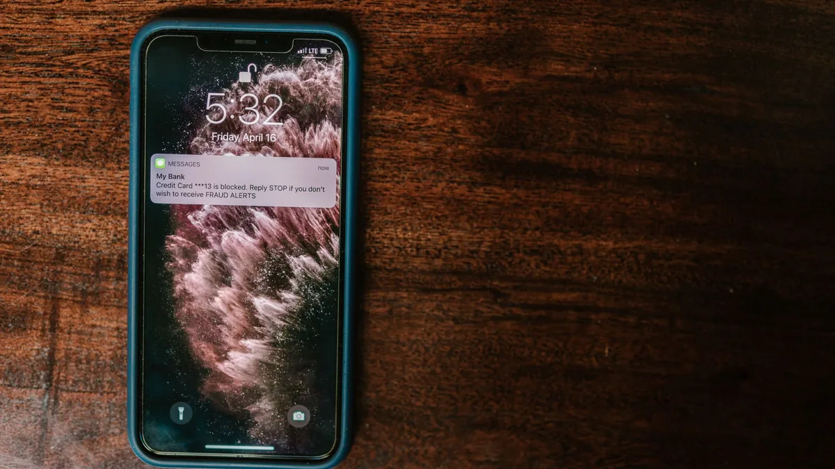 Smartphone on a wooden table showing an alert on the lock screen