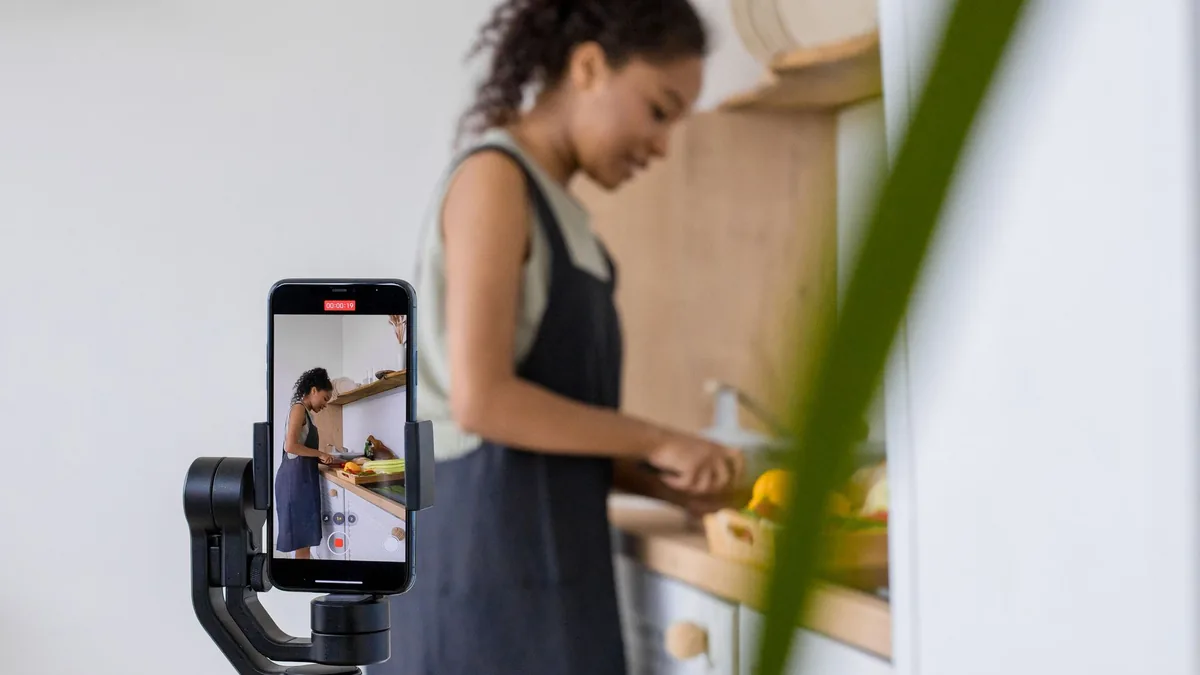 Woman filming a cooking video on a smartphone on a gimbal in her kitchen
