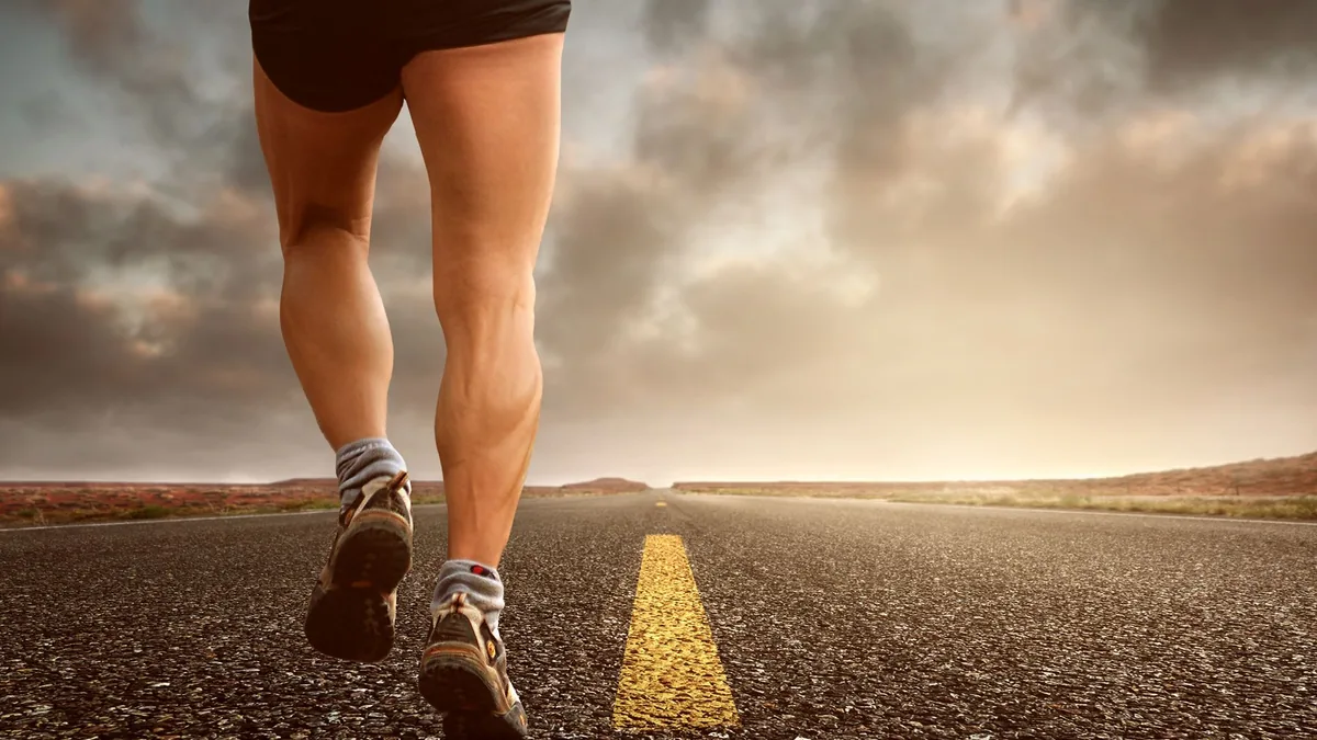 Runner's legs on an empty road at sunset