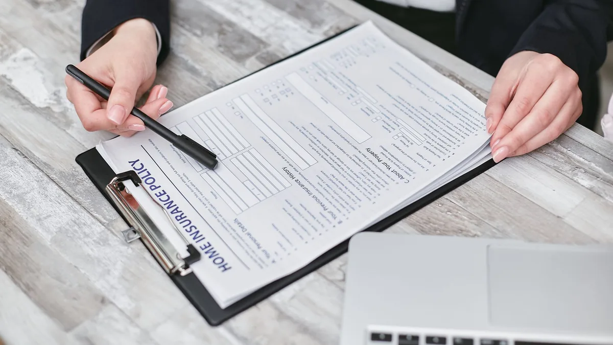 Hands reviewing a home insurance policy document on a clipboard