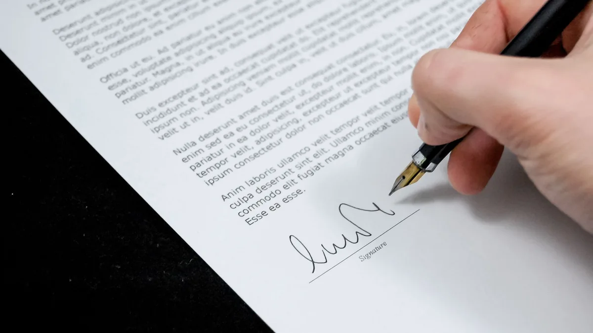 Hand signing an official document with a fountain pen