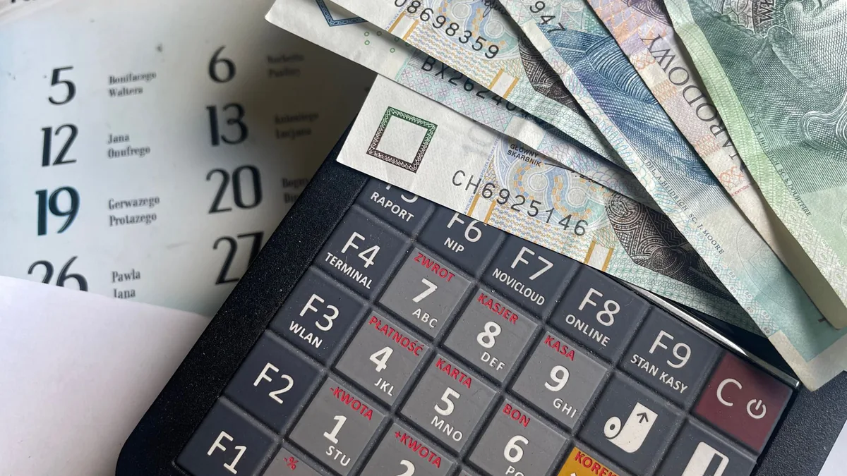 Banknotes resting on a calculator with a calendar in the background